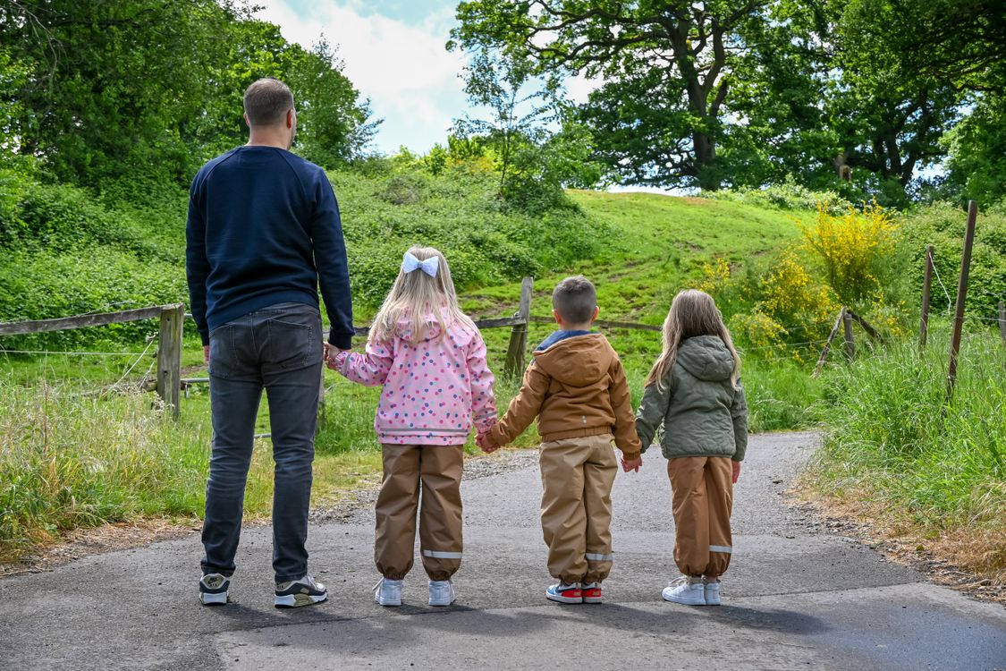 A father holding hands with children on a nature trail
